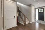 Step into this inviting entryway featuring a modern staircase with dark wood railings and sleek black spindles.