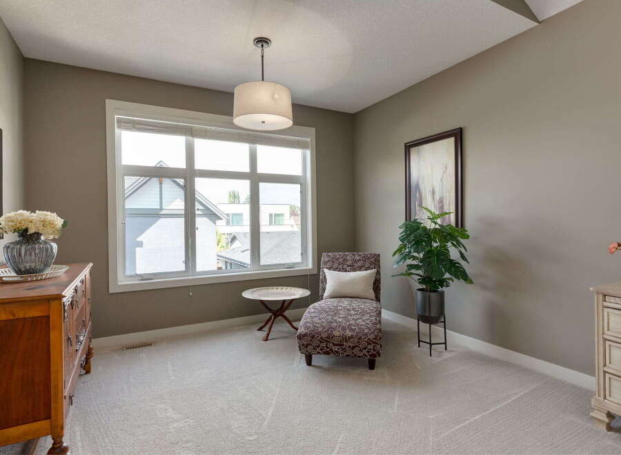 This inviting room features a large window that floods the space with natural light, highlighting the plush carpeting and elegant decor.