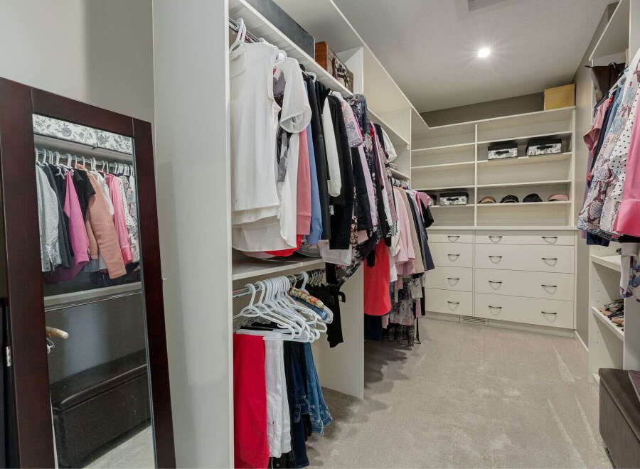 Step into this spacious walk-in closet, meticulously organized with ample hanging space and built-in shelving.