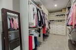 Step into this spacious walk-in closet, meticulously organized with ample hanging space and built-in shelving.