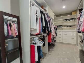Step into this spacious walk-in closet, meticulously organized with ample hanging space and built-in shelving.