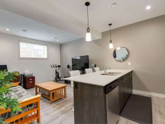 This modern living space features a sleek kitchen island with a double sink and stainless steel dishwasher, perfect for entertaining.