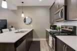 This modern kitchen features sleek, dark wood cabinetry complemented by a bright white quartz countertop and backsplash.