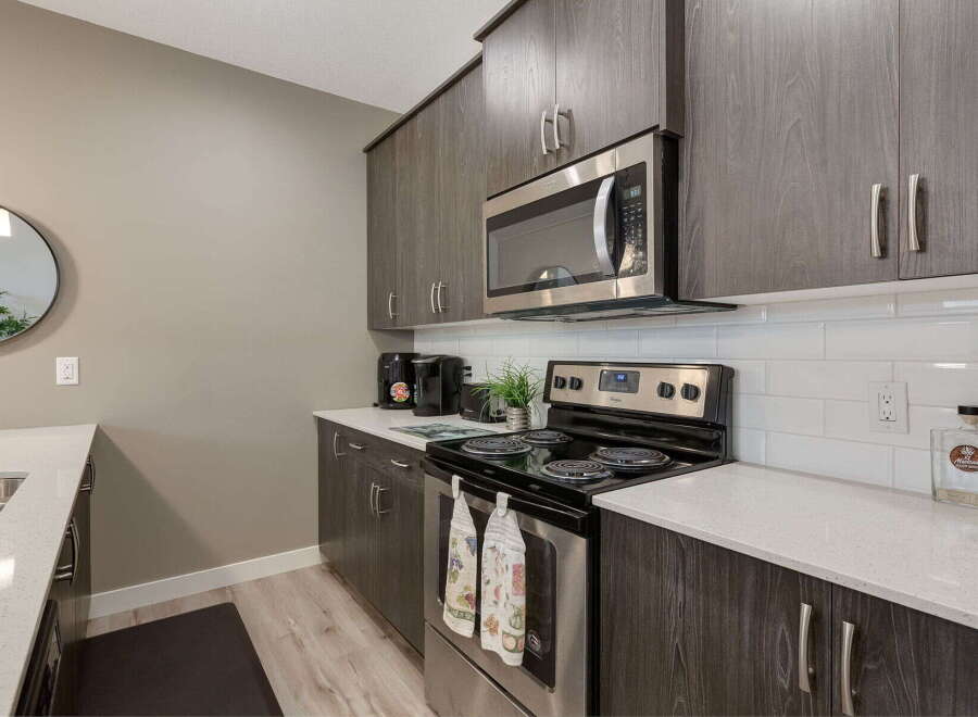 Discover this modern kitchen featuring sleek, dark wood cabinetry and a stainless steel microwave.