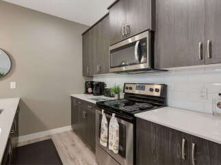 Discover this modern kitchen featuring sleek, dark wood cabinetry and a stainless steel microwave.
