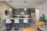This modern kitchen features sleek, dark wood cabinetry and a spacious island with white bar stools, perfect for casual dining or entertaining.
