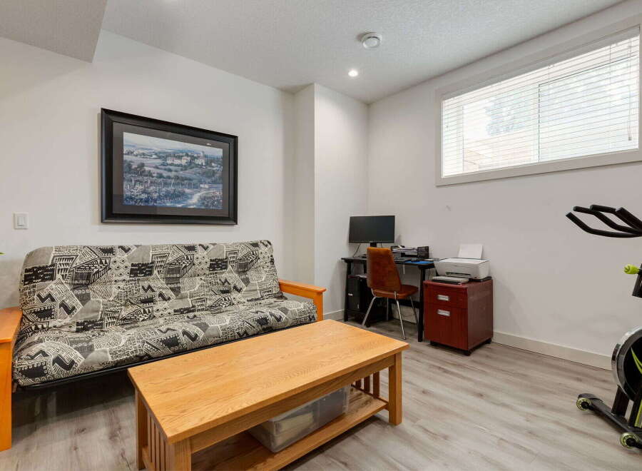 This versatile room features a comfortable futon, perfect for guests or lounging, alongside a functional workspace with a desk, computer, and printer.