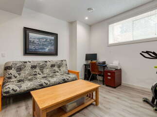 This versatile room features a comfortable futon, perfect for guests or lounging, alongside a functional workspace with a desk, computer, and printer.