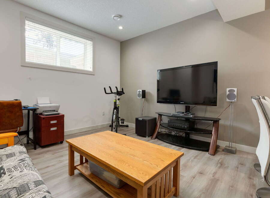 This versatile room offers a perfect blend of relaxation and productivity, featuring a large flat-screen TV for entertainment and a dedicated workspace with a printer.