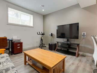 This versatile room offers a perfect blend of relaxation and productivity, featuring a large flat-screen TV for entertainment and a dedicated workspace with a printer.