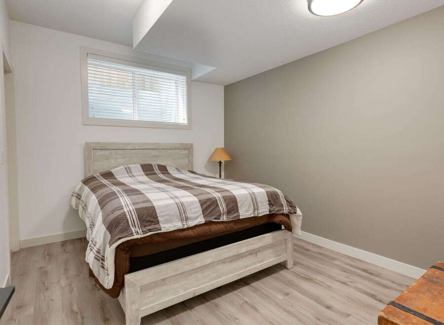 Discover comfort and style in this inviting bedroom, featuring a cozy bed with a classic plaid comforter.