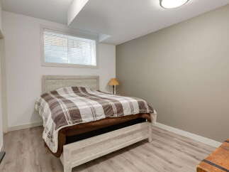 Discover comfort and style in this inviting bedroom, featuring a cozy bed with a classic plaid comforter.