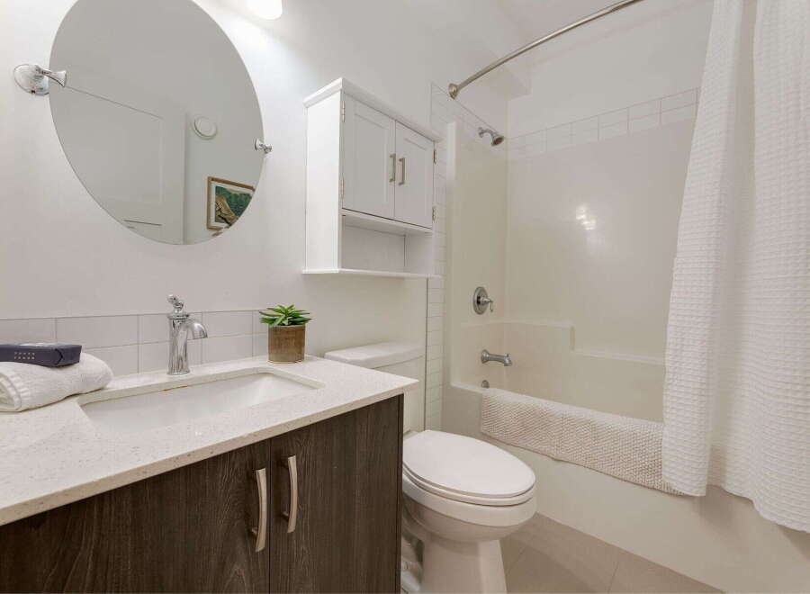 This modern bathroom features a sleek vanity with a quartz countertop and dark wood cabinetry, complemented by a stylish chrome faucet.