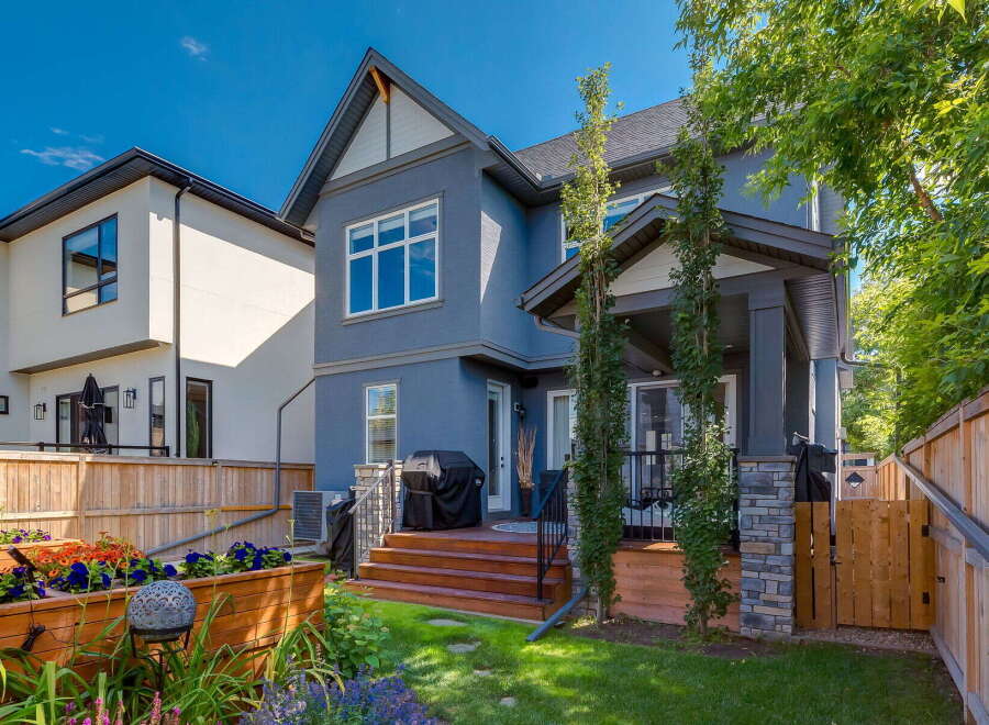 This stunning backyard features a spacious wooden deck with a covered patio area, perfect for outdoor entertaining.