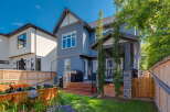 This stunning backyard features a spacious wooden deck with a covered patio area, perfect for outdoor entertaining.