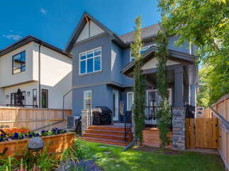 This stunning backyard features a spacious wooden deck with a covered patio area, perfect for outdoor entertaining.