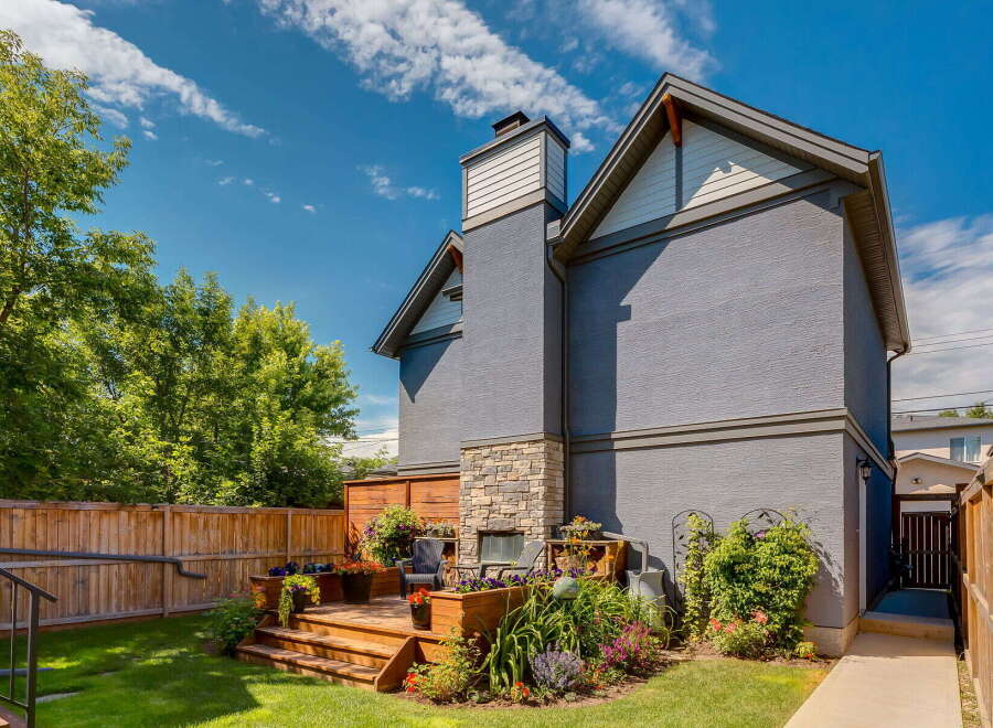 Enjoy outdoor living in this charming backyard featuring a multi-level wooden deck with built-in planters and a stone-accented fireplace.
