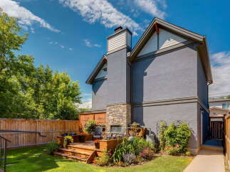 Enjoy outdoor living in this charming backyard featuring a multi-level wooden deck with built-in planters and a stone-accented fireplace.