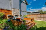 Enjoy outdoor living in this beautifully landscaped backyard featuring a multi-level wooden deck with built-in planters overflowing with colorful flowers.
