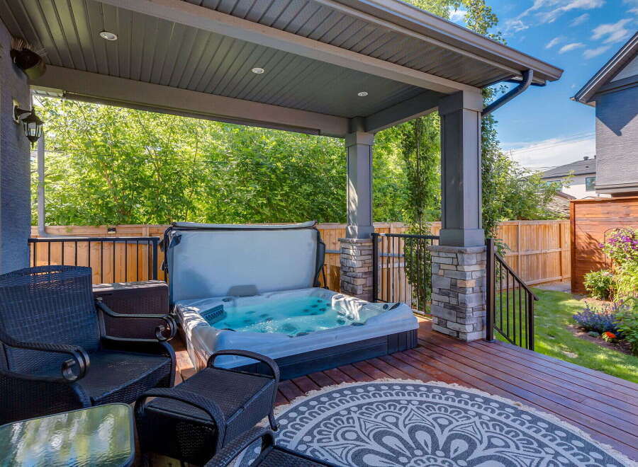 Enjoy ultimate relaxation in this covered backyard oasis, featuring a luxurious hot tub perfect for unwinding.