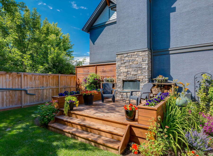Enjoy outdoor living in this charming backyard oasis, featuring a multi-level wooden deck perfect for entertaining.