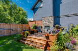Enjoy outdoor living in this charming backyard oasis, featuring a multi-level wooden deck perfect for entertaining.
