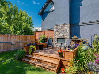 Enjoy outdoor living in this charming backyard oasis, featuring a multi-level wooden deck perfect for entertaining.
