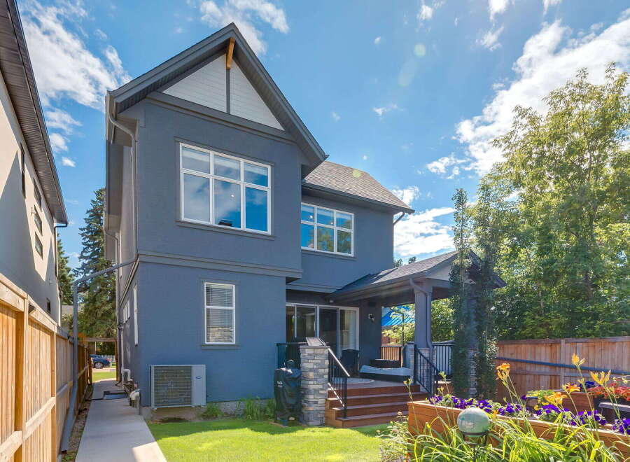Discover this stunning modern home featuring a sleek dark blue exterior and a spacious backyard perfect for entertaining.