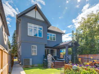 Discover this stunning modern home featuring a sleek dark blue exterior and a spacious backyard perfect for entertaining.