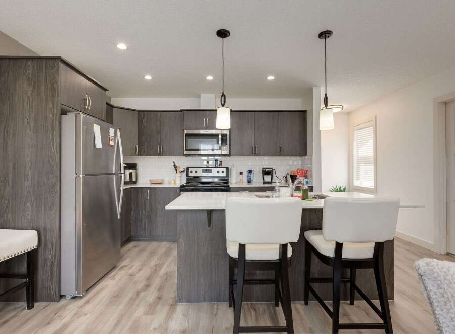 Discover this modern kitchen featuring sleek, dark wood cabinetry and a spacious island perfect for casual dining or entertaining.