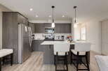 Discover this modern kitchen featuring sleek, dark wood cabinetry and a spacious island perfect for casual dining or entertaining.