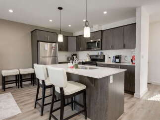 Discover this modern kitchen featuring sleek dark wood cabinetry and a spacious quartz island perfect for meal prep and casual dining.