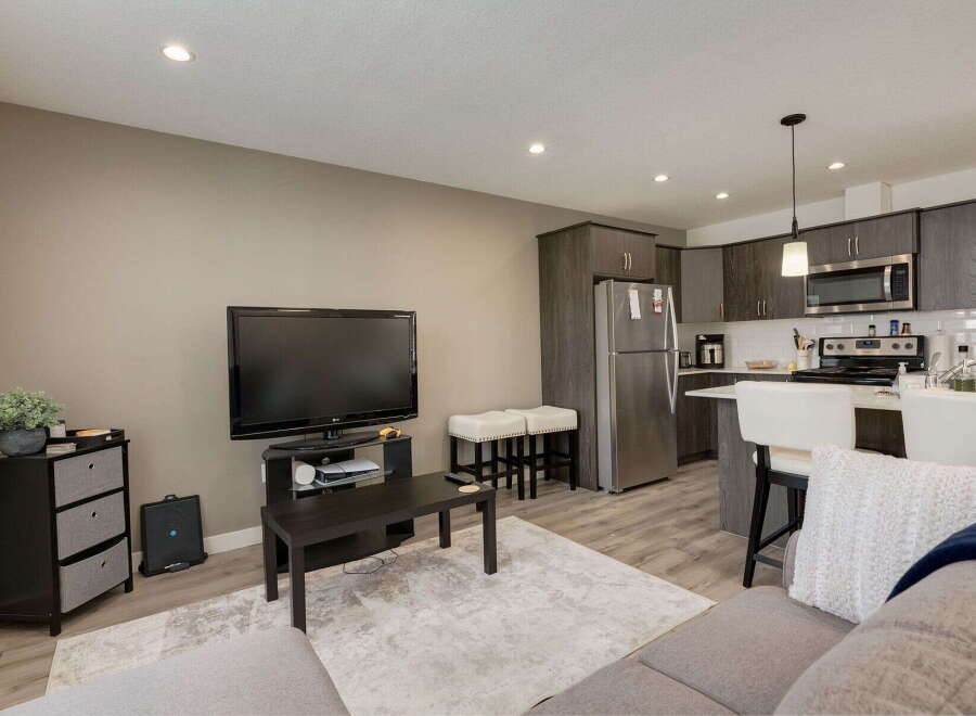 Experience modern living in this stylish open-concept space, featuring a sleek kitchen with stainless steel appliances and ample cabinet storage.