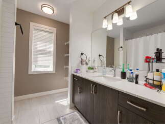 This modern bathroom features a sleek dark wood vanity with a white quartz countertop, offering ample storage and a clean aesthetic.