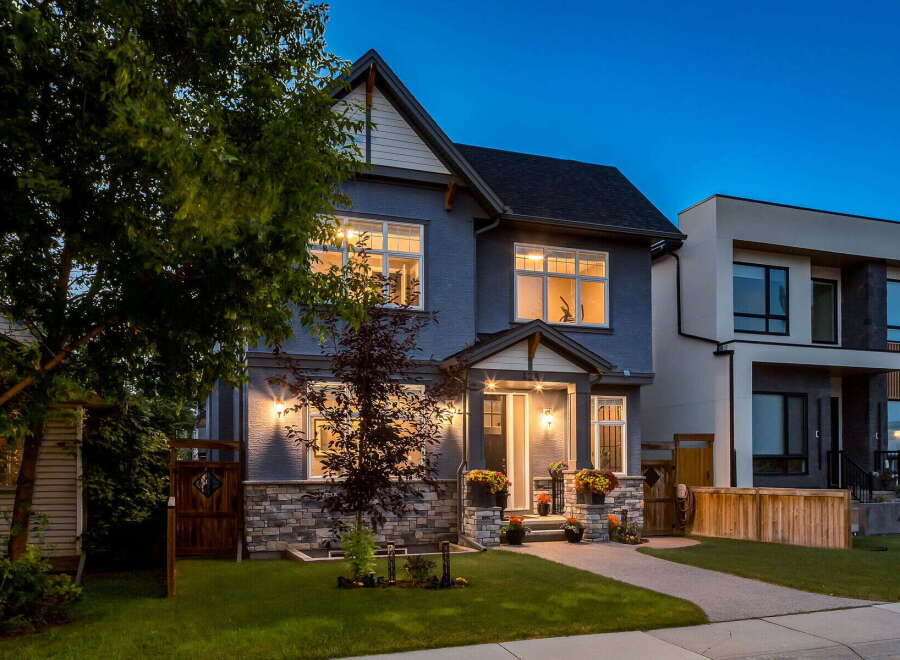 This stunning modern home features a striking grey stucco exterior accented by a stone base and a welcoming covered porch.