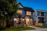 This stunning modern home features a striking grey stucco exterior accented by a stone base and a welcoming covered porch.
