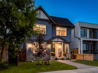 This stunning modern home features a striking grey stucco exterior accented by a stone base and a welcoming covered porch.