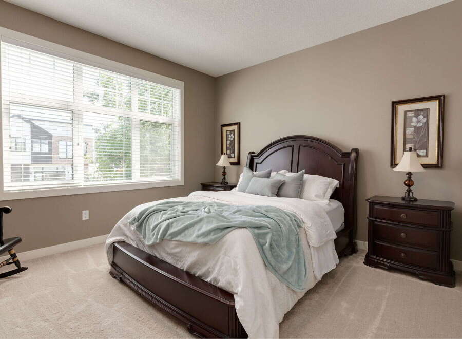 Experience comfort and style in this beautifully appointed bedroom, featuring a spacious dark wood bed frame and matching nightstands.