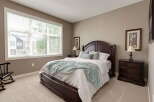 Experience comfort and style in this beautifully appointed bedroom, featuring a spacious dark wood bed frame and matching nightstands.