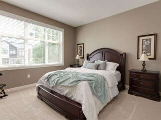 Experience comfort and style in this beautifully appointed bedroom, featuring a spacious dark wood bed frame and matching nightstands.
