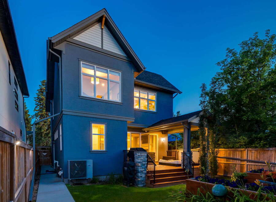 This stunning modern home features a striking blue exterior and a spacious backyard deck perfect for entertaining.