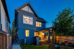 This stunning modern home features a striking blue exterior and a spacious backyard deck perfect for entertaining.