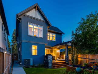 This stunning modern home features a striking blue exterior and a spacious backyard deck perfect for entertaining.
