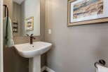 This powder room features a stylish pedestal sink with a bronze faucet, complemented by a large vanity mirror.