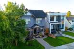 Discover modern living in this stunning blue stucco home, featuring a welcoming covered porch with stone accents and ample natural light through large windows.