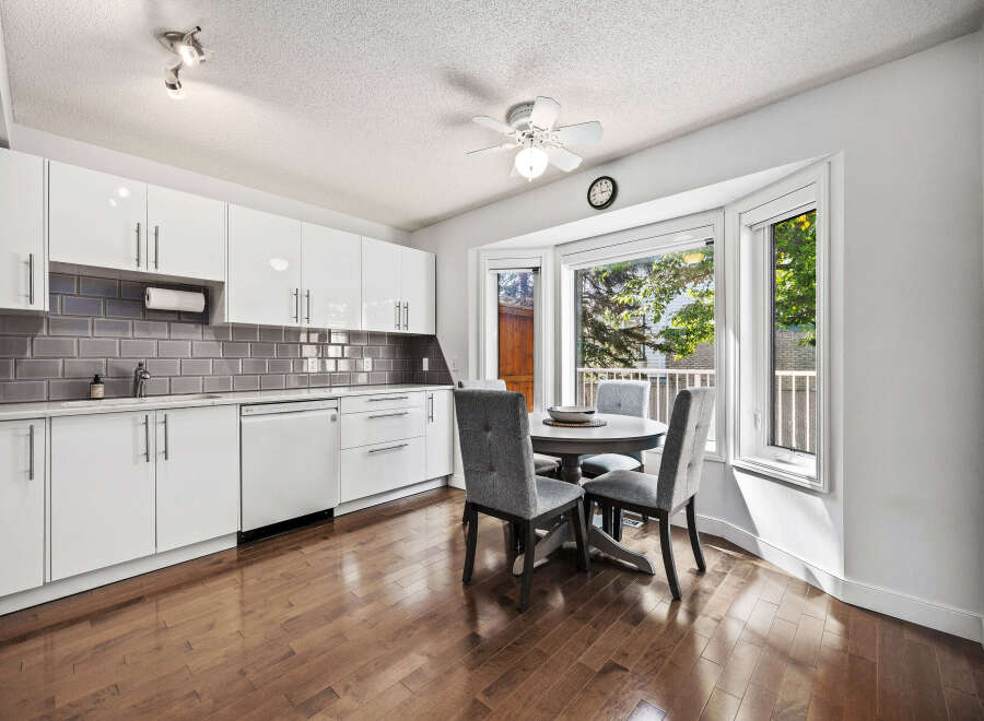 Bright and modern kitchen featuring sleek white cabinetry, a stylish grey subway tile backsplash, and a charming breakfast nook.