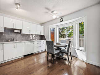 Bright and modern kitchen featuring sleek white cabinetry, a stylish grey subway tile backsplash, and a charming breakfast nook.