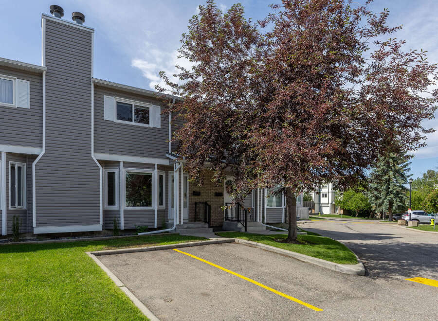 Discover comfortable living in this charming townhouse featuring a prominent exterior chimney and a beautiful mature tree providing shade and curb appeal.