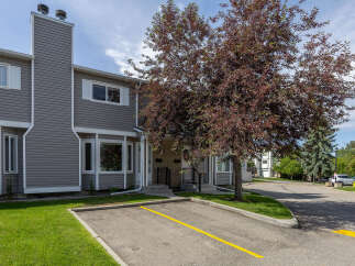 Discover comfortable living in this charming townhouse featuring a prominent exterior chimney and a beautiful mature tree providing shade and curb appeal.