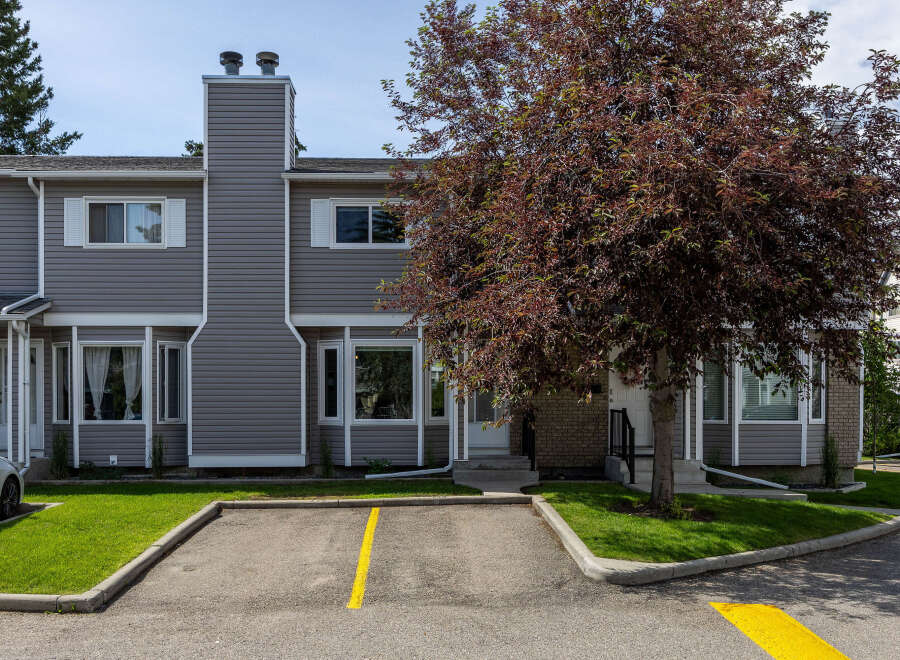 Discover comfortable living in this charming townhouse featuring a modern grey siding exterior and a prominent brick entrance.